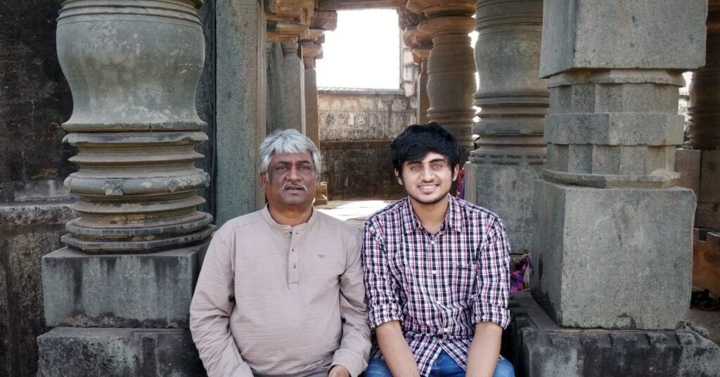 Aniruddh Aithal seated at a stone temple mandapa with a senior musician