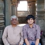 Aniruddh Aithal seated at a stone temple mandapa with a senior musician
